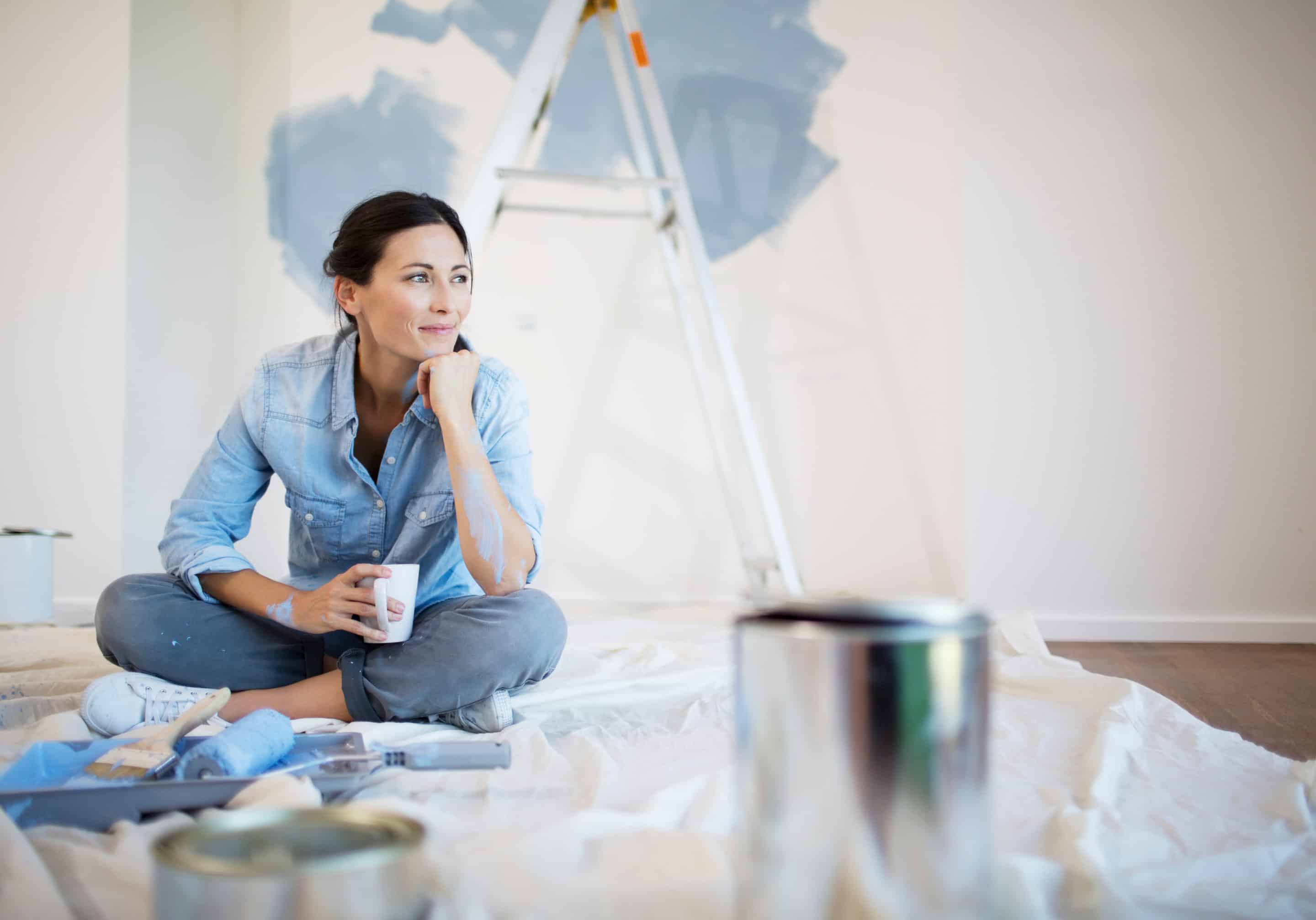 Travaux de peinture en cours, une femme détendue avec une tasse, symbolisant la reconstruction après une relation toxique.