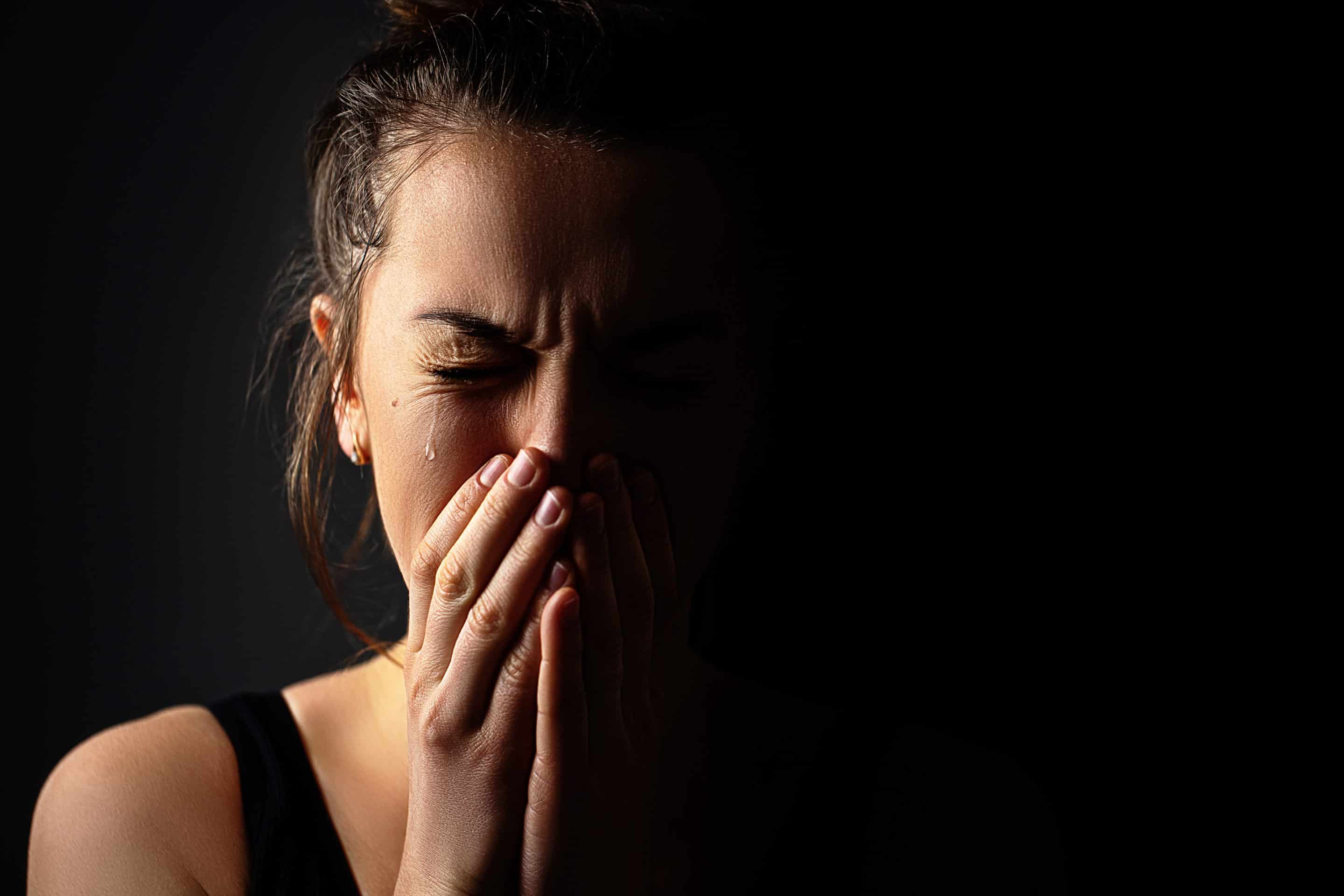 Femme se couvrant le visage en pleurant, illustrant l’impact du stress post-traumatique lié à un pervers narcissique