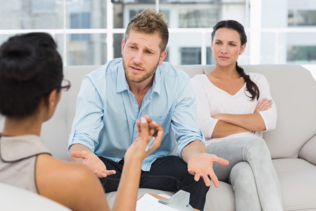 Scène de thérapie de couple avec un homme expressif et une femme distante, évoquant les défis spécifiques avec un pervers narcissique.