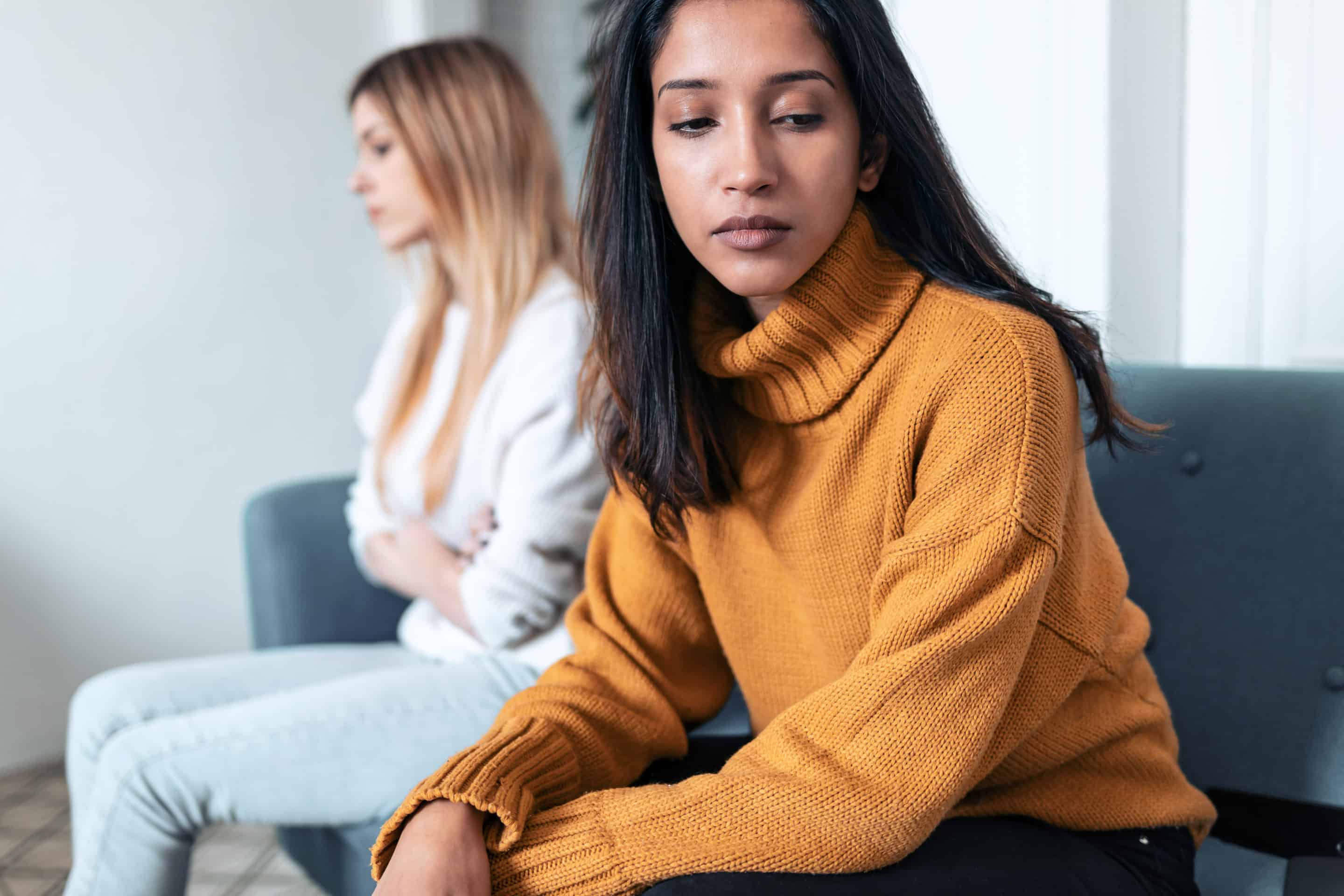 Deux amies assises en silence, l'une regardant ailleurs, symbolisant une relation amicale tendue et toxique.