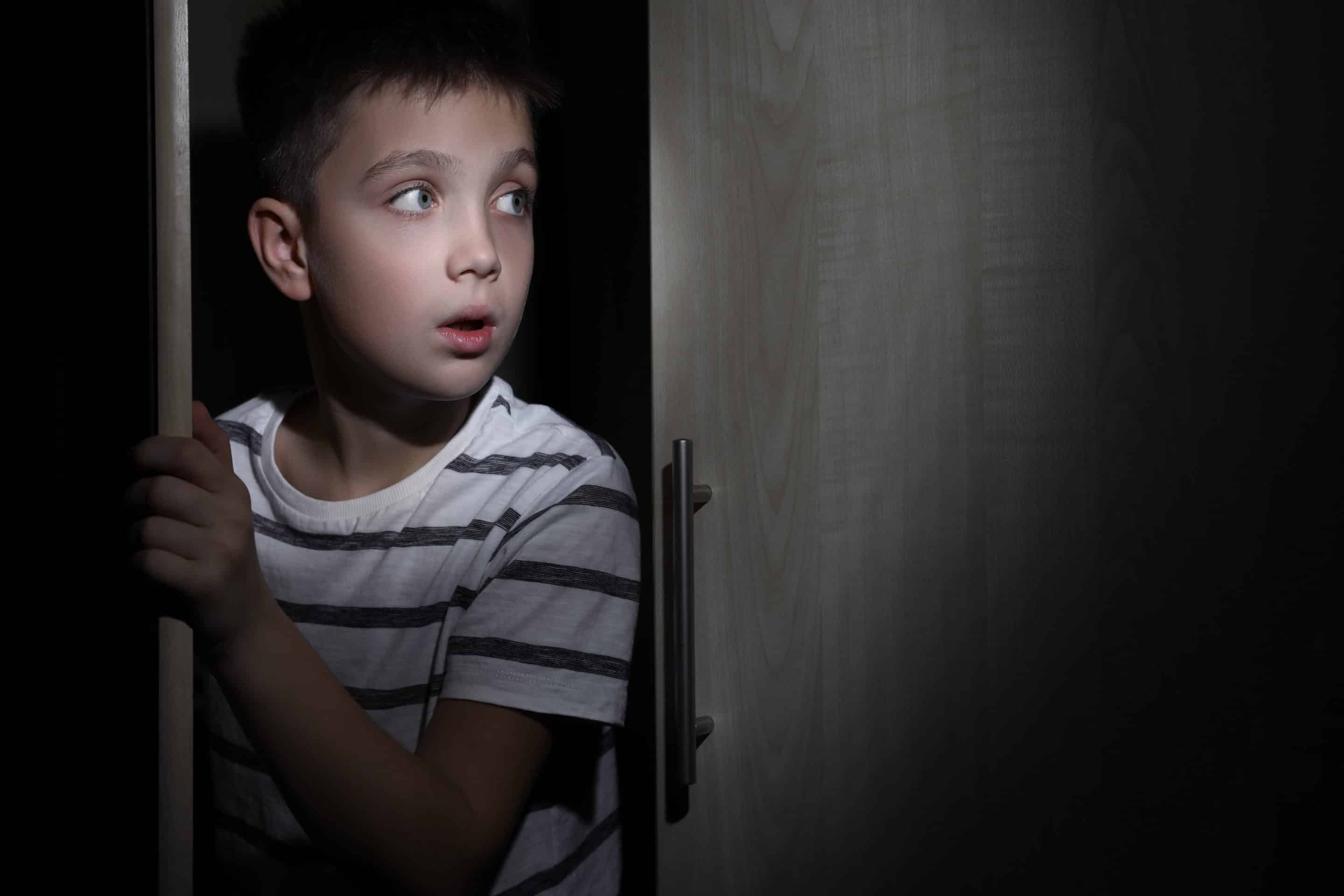 Portrait d’un jeune garçon observant avec appréhension, symbolisant l’importance des premières expériences dans la vie.