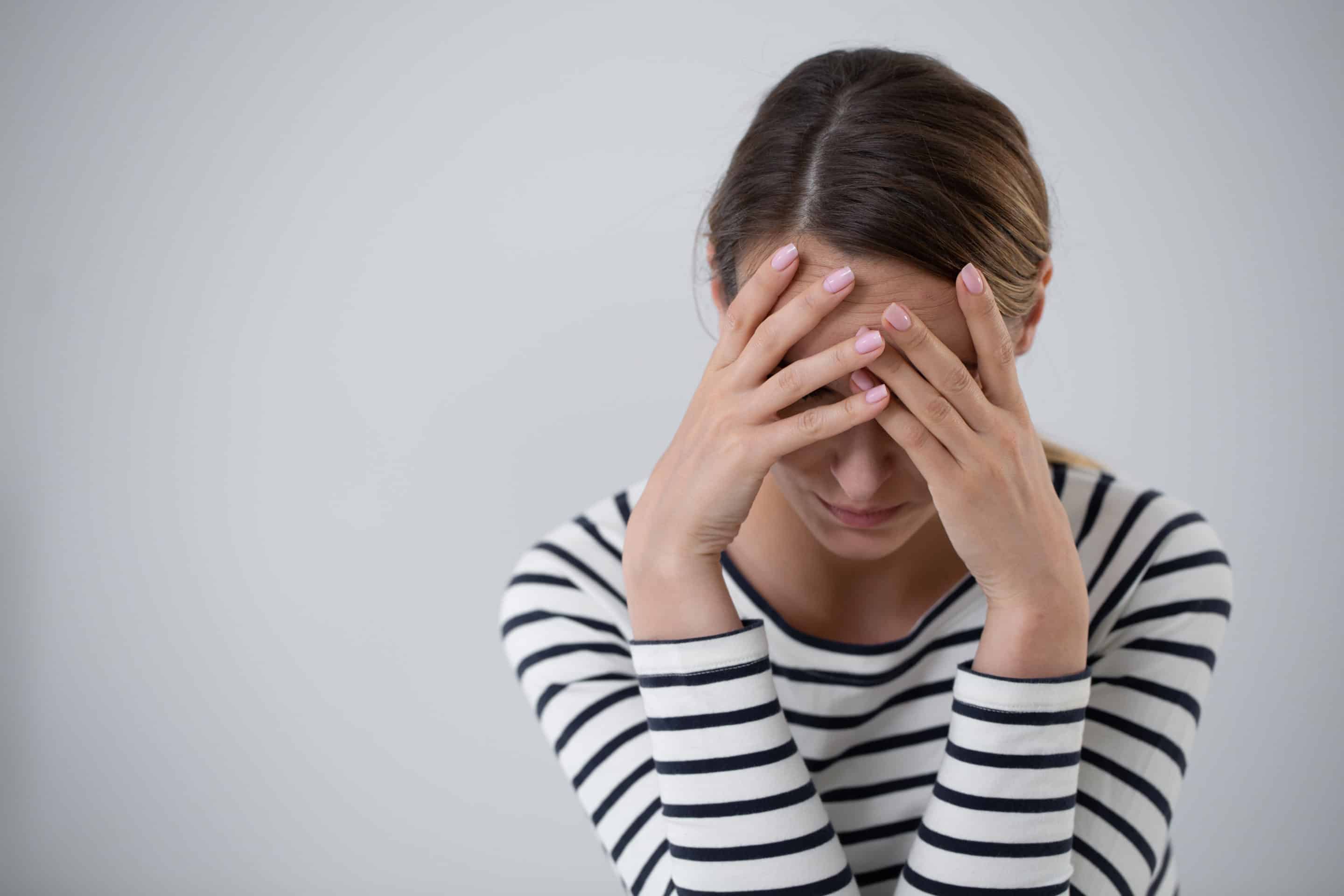 Portrait d’une femme se tenant la tête, subissant le poids de la culpabilisation dans une relation toxique.