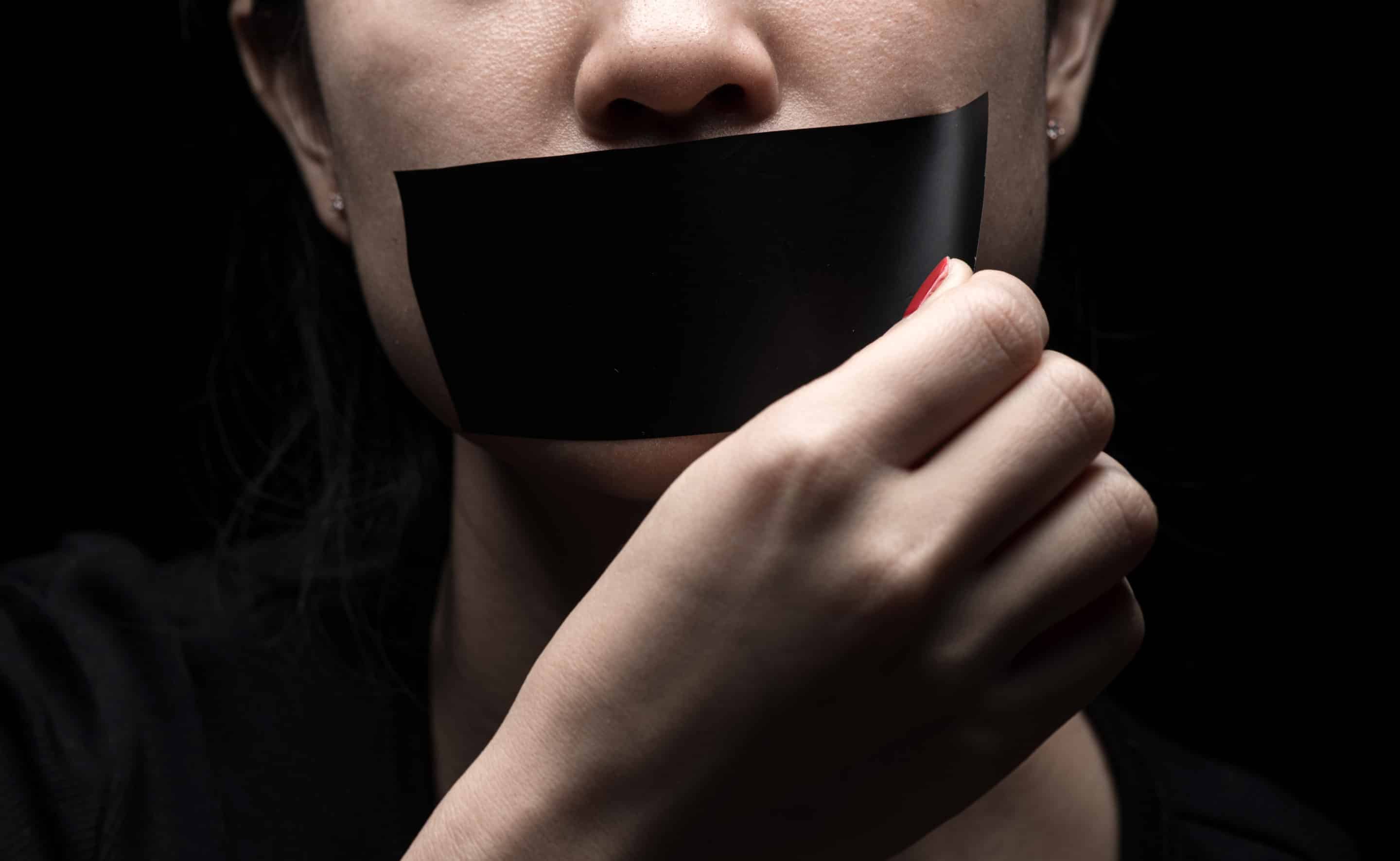 Portrait en gros plan d’une personne bâillonnée, incarnant le contrôle et l’interdiction de s’exprimer dans une relation toxique.