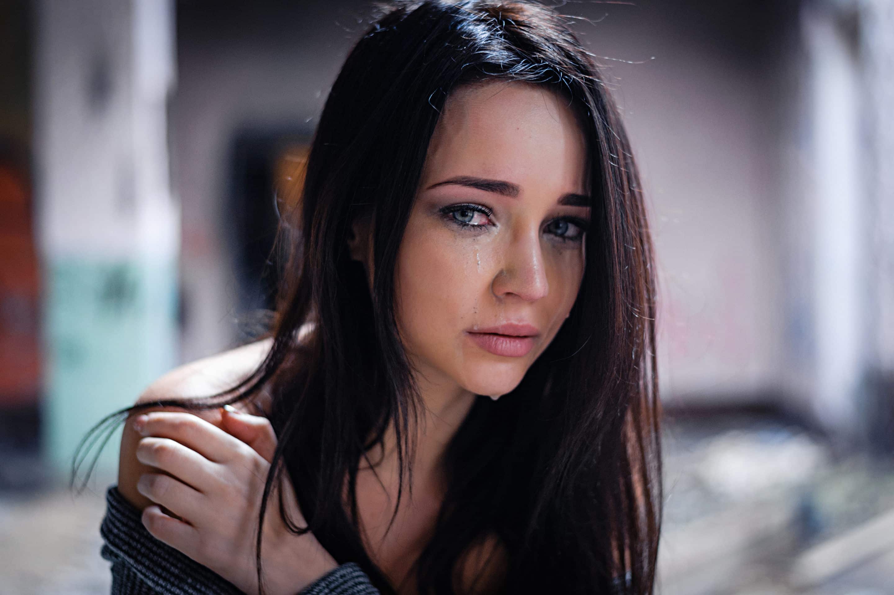 Portrait d’une femme vulnérable, des larmes sur le visage, illustrant l’impact émotionnel du dénigrement dans une relation toxique.