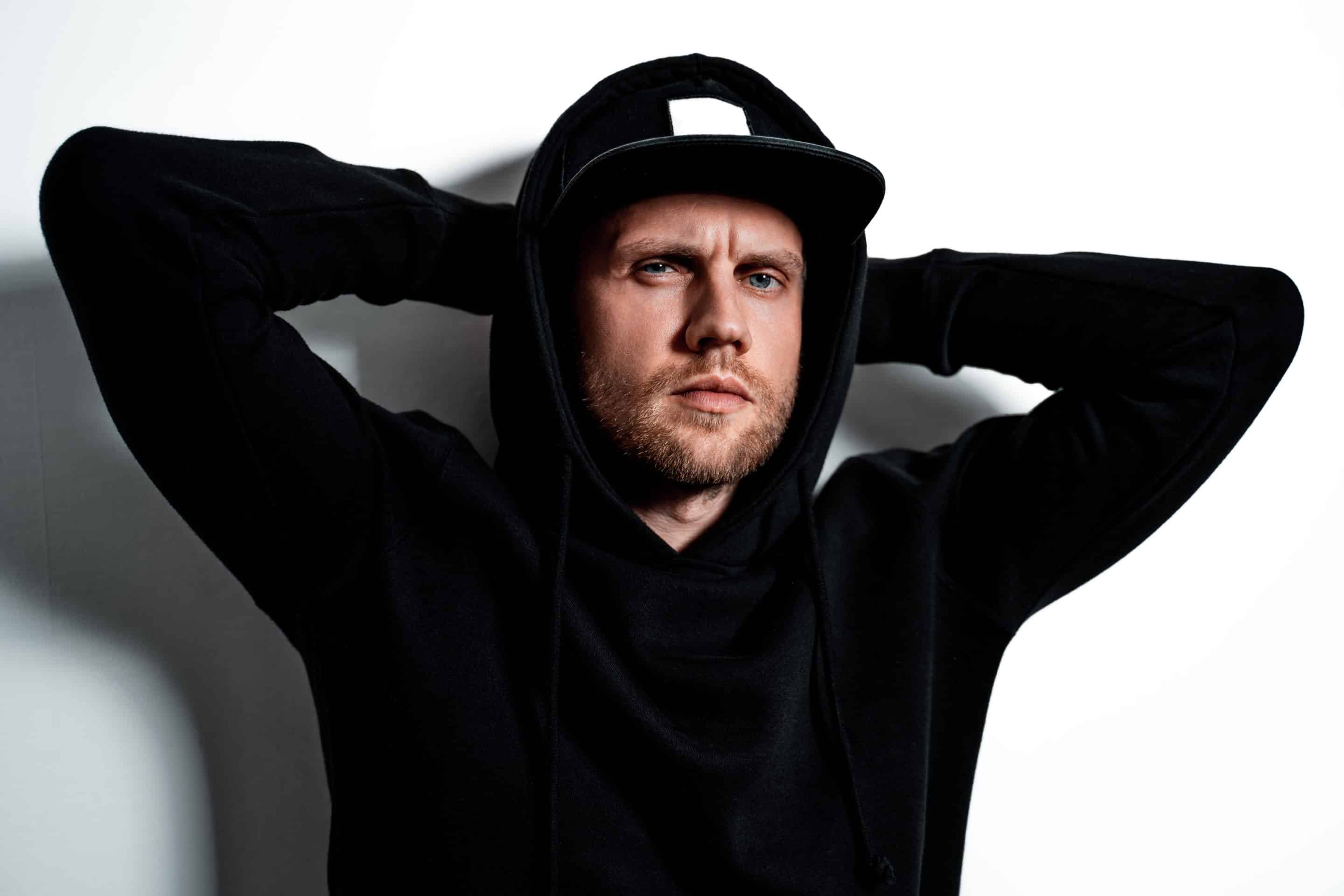 Un homme portant une capuche noire, regard intense et attitude fermée, illustrant une personnalité passive-agressive.