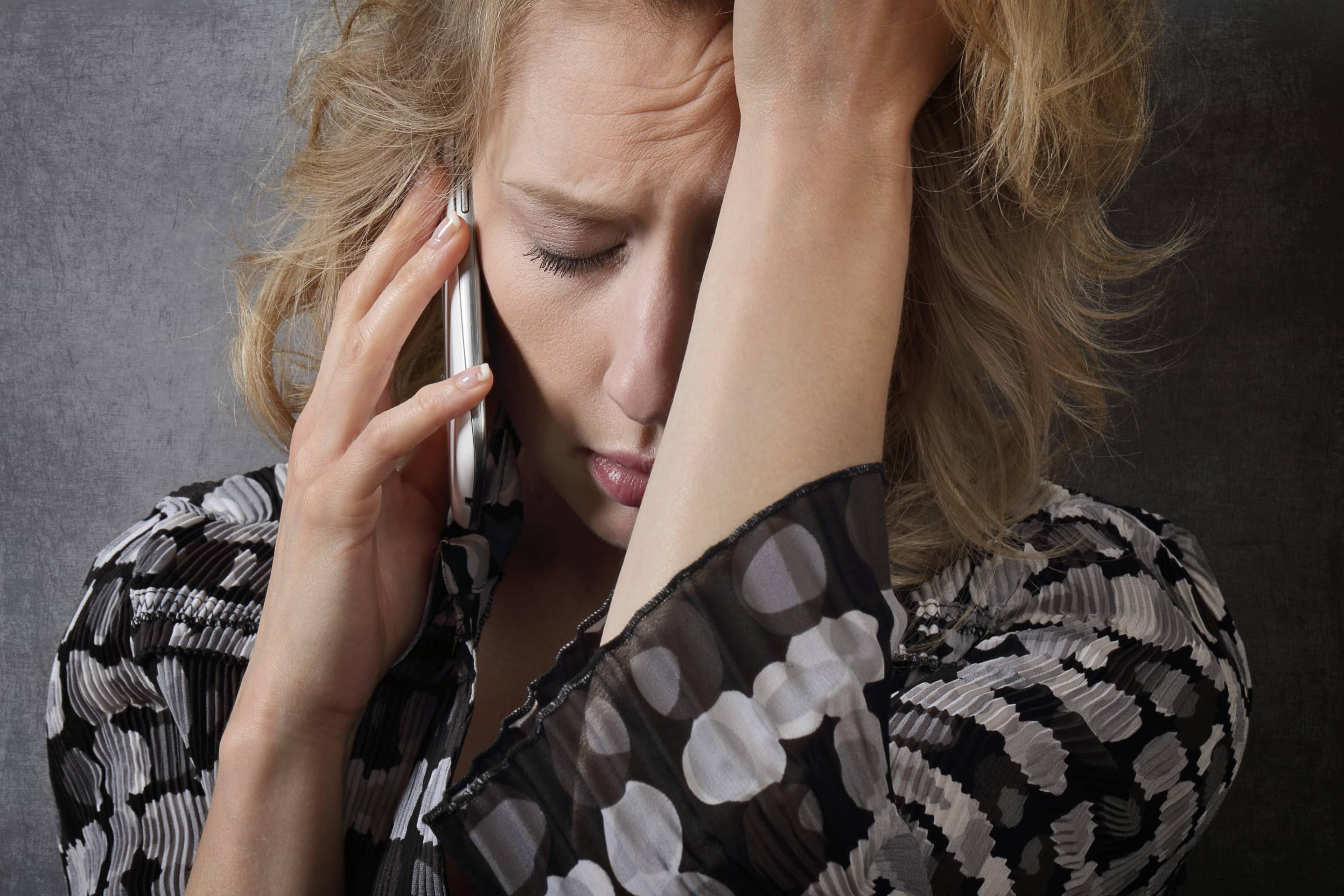 Femme angoissée au téléphone, symbolisant l’hésitation à prévenir la nouvelle victime d’un pervers narcissique.