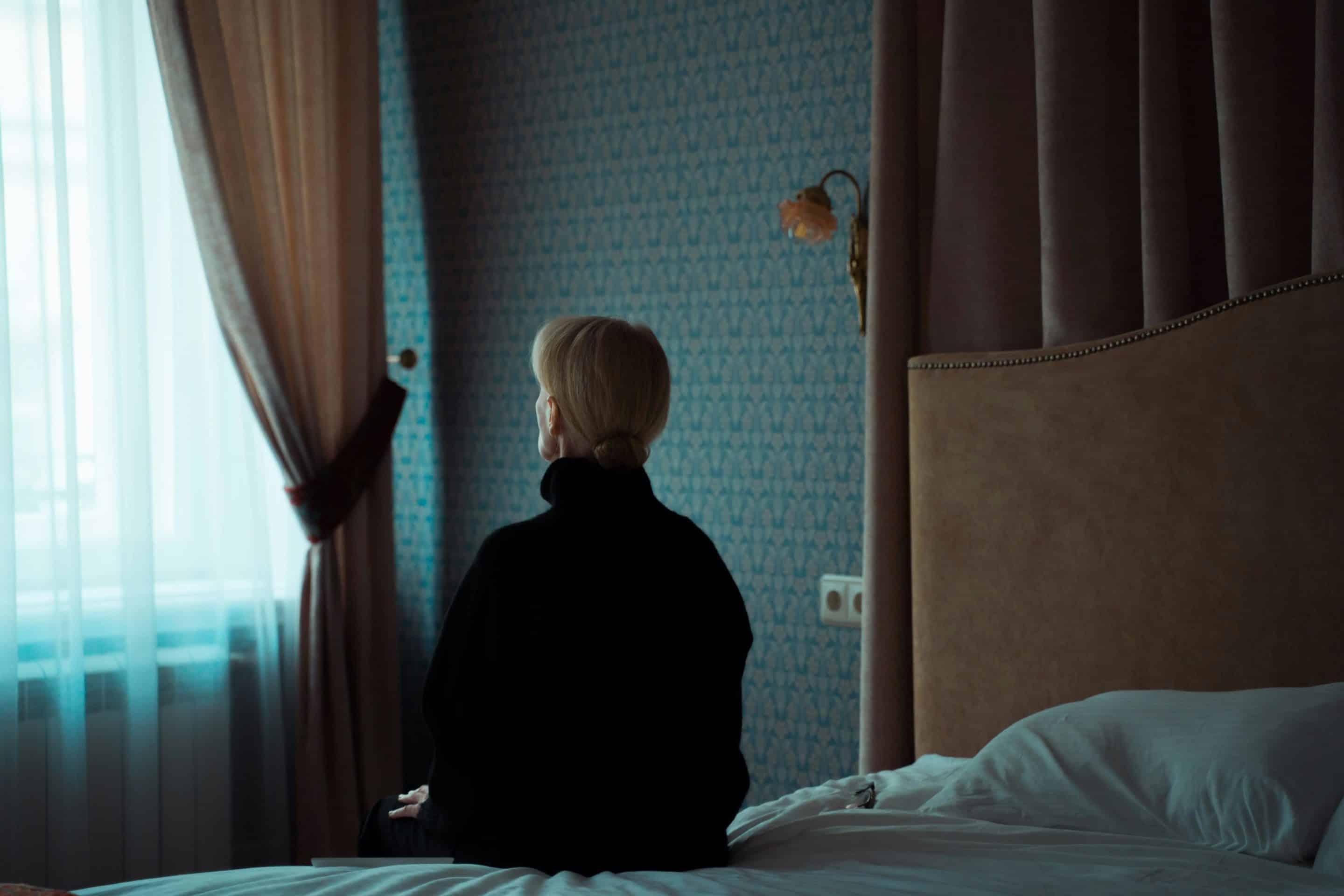 Une personne assise seule, contemplant la fenêtre dans un environnement calme, symbolisant l'isolement et la réflexion intérieure face à l'angoisse d'abandon.