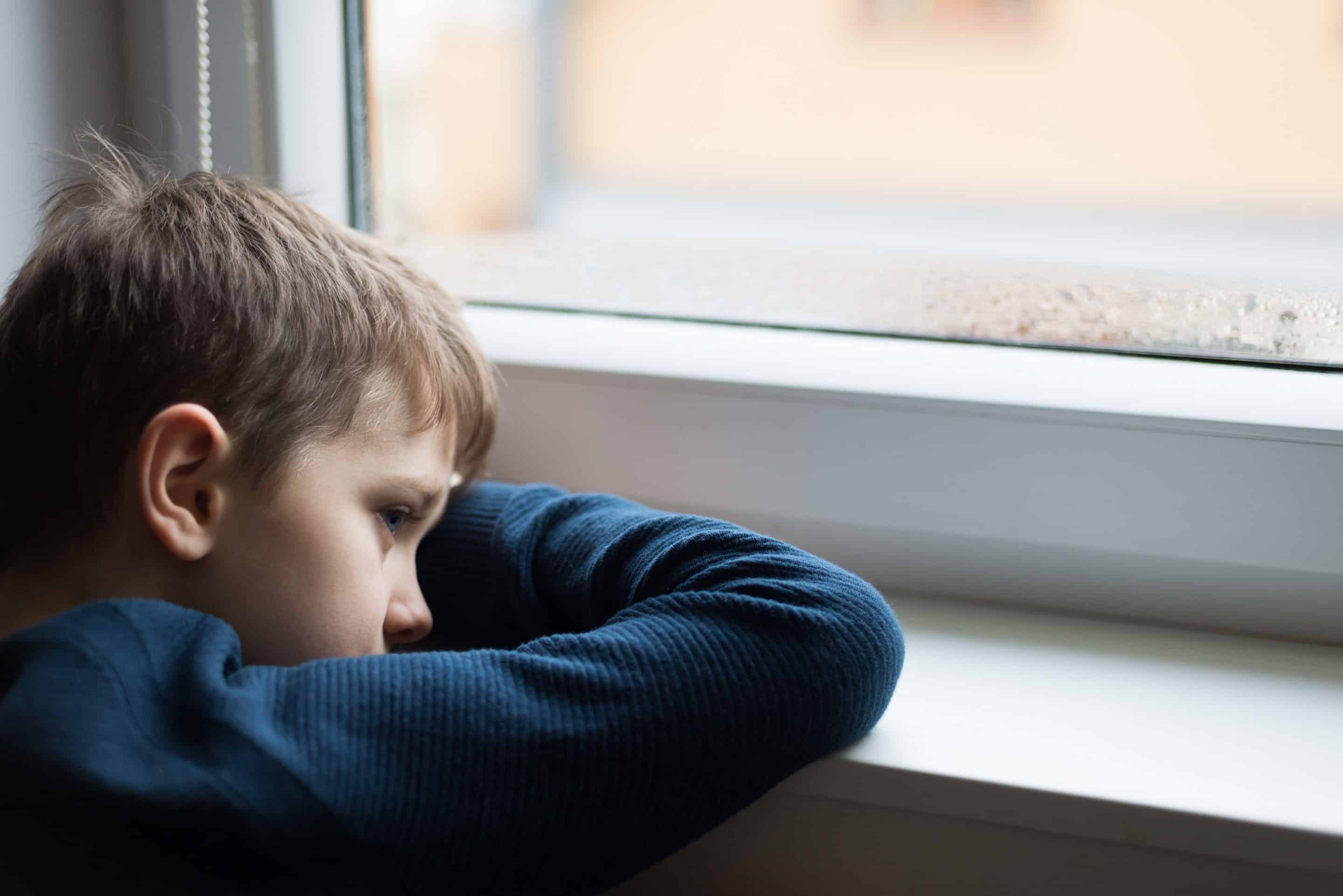 Enfant triste assis seul, représentant la dynamique du favoritisme toxique d'un parent manipulateur.