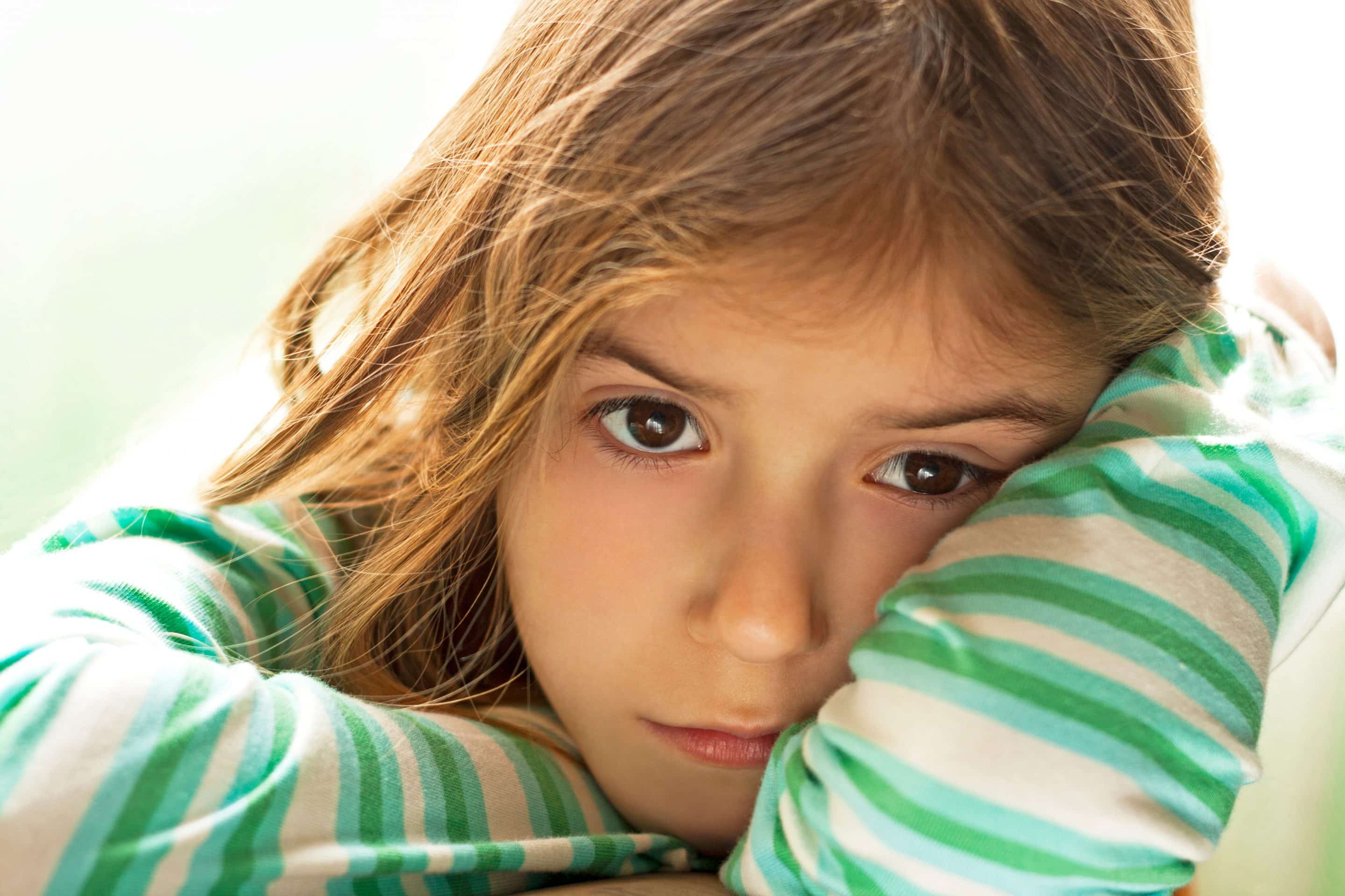Jeune enfant au regard triste, la tête posée sur ses bras, illustrant le sentiment d’abandon et de solitude dans une famille toxique.