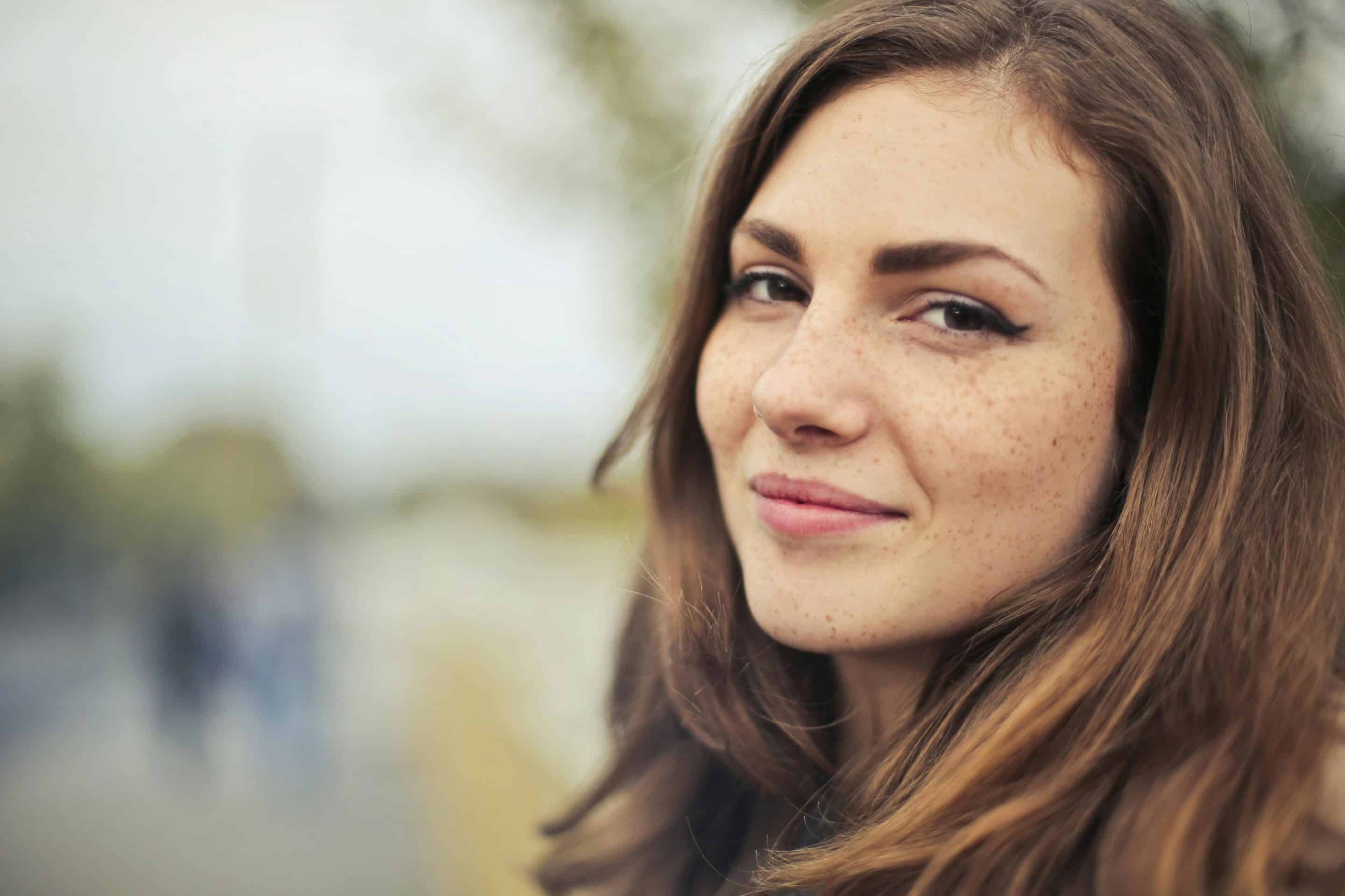 Portrait d’une jeune femme au regard doux et confiant, esquissant un léger sourire, symbole de la reconstruction d’une image de soi apaisée.