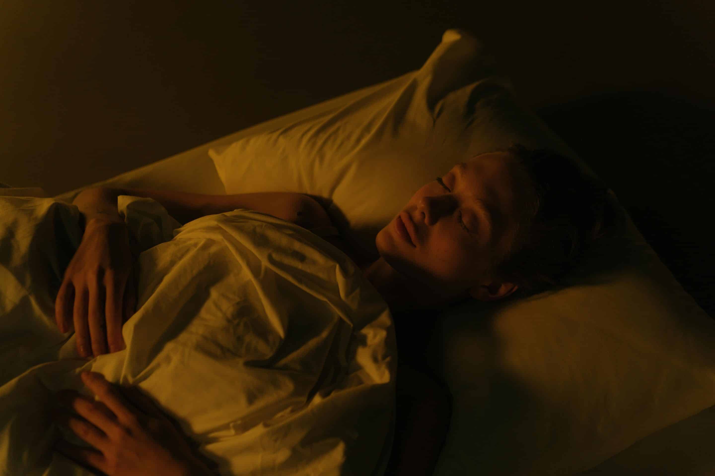 Femme épuisée allongée dans son lit la nuit, victime de privation de sommeil par pervers narcissique